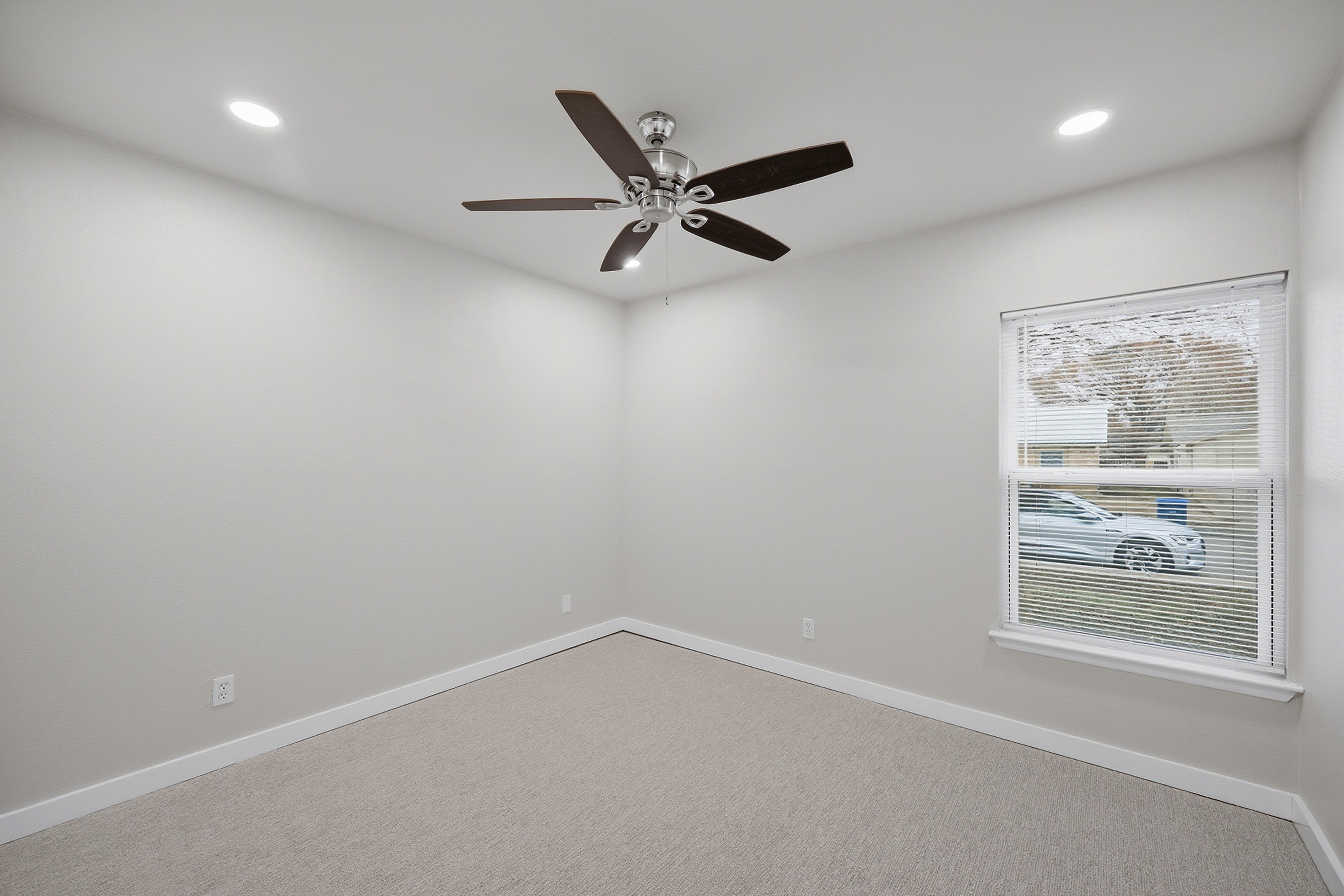 Fourth bedroom with ceiling fan, natural light, and neutral carpet